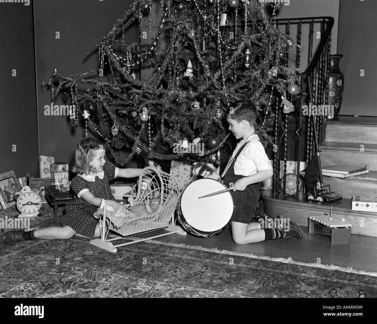 1930s 1940s un ragazzo e una ragazza a giocare con i giocattoli e presenta DA ALBERO DI NATALE Foto Stock