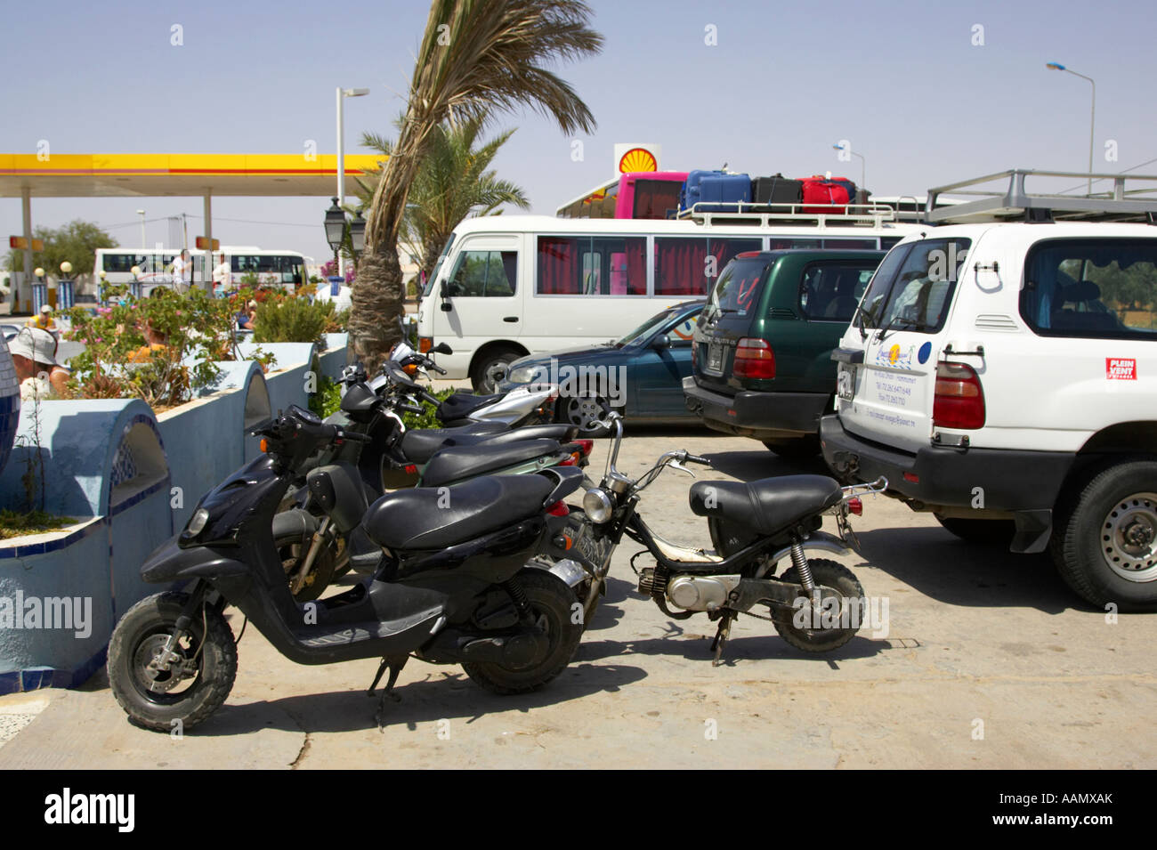 Linea di ciclomotori e di trasporto turistico veicoli in sosta alla stazione di servizio in autostrada in Tunisia Foto Stock