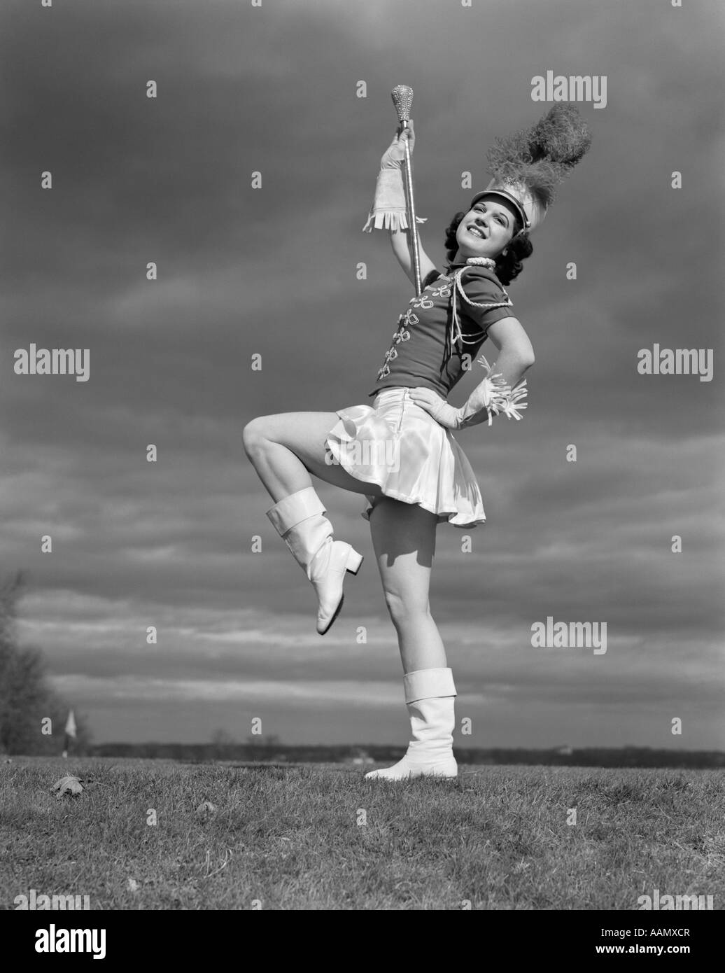 1940s donna grande tamburo IN BANDA MAJORETTE uniforme fa roteare BATON indossando guanti di frange cappello con pennacchio di piume stivali bianco Foto Stock