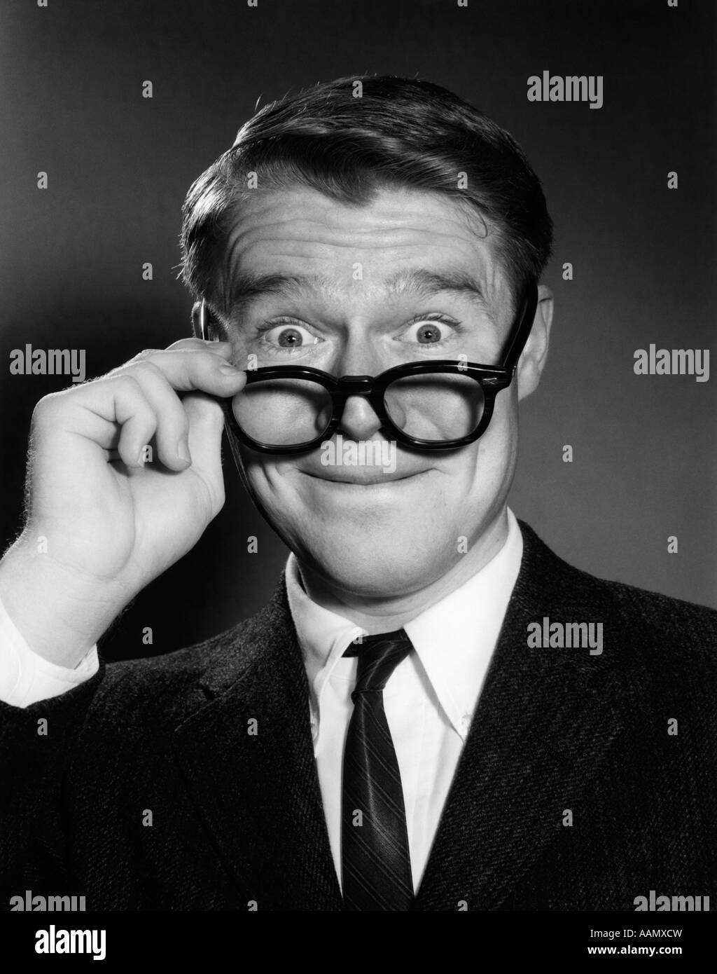 Anni sessanta sorpreso giovane imprenditore tenendo fuori i suoi occhiali uomo divertente faccia del viso espressione meravigliato stupore stupore stupore Foto Stock