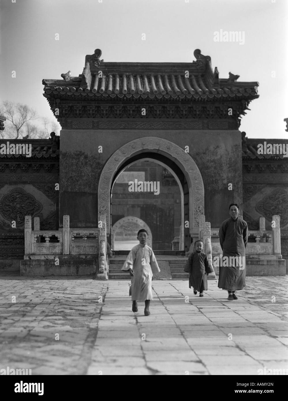 1920s 1930 uomo cinese 2 bambini ragazzi a piedi dal Tempio del Gateway Arch WINTER PALACE Pechino Pechino CINA Foto Stock