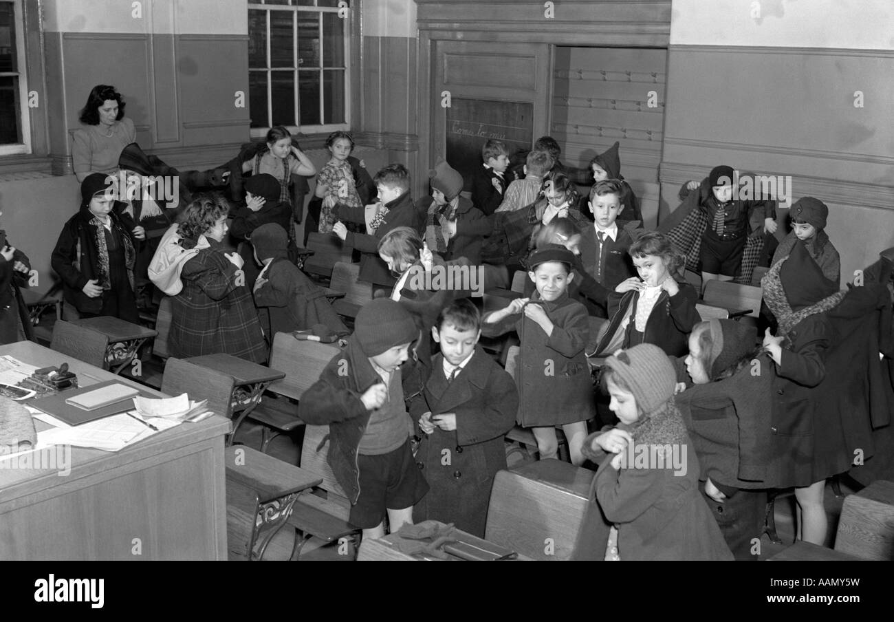 1940s scuola bambini mettendo sul loro cappotti A LASCIARE LA CLASSE PER RECESSO Ragazzi Ragazze studenti istruzione Foto Stock