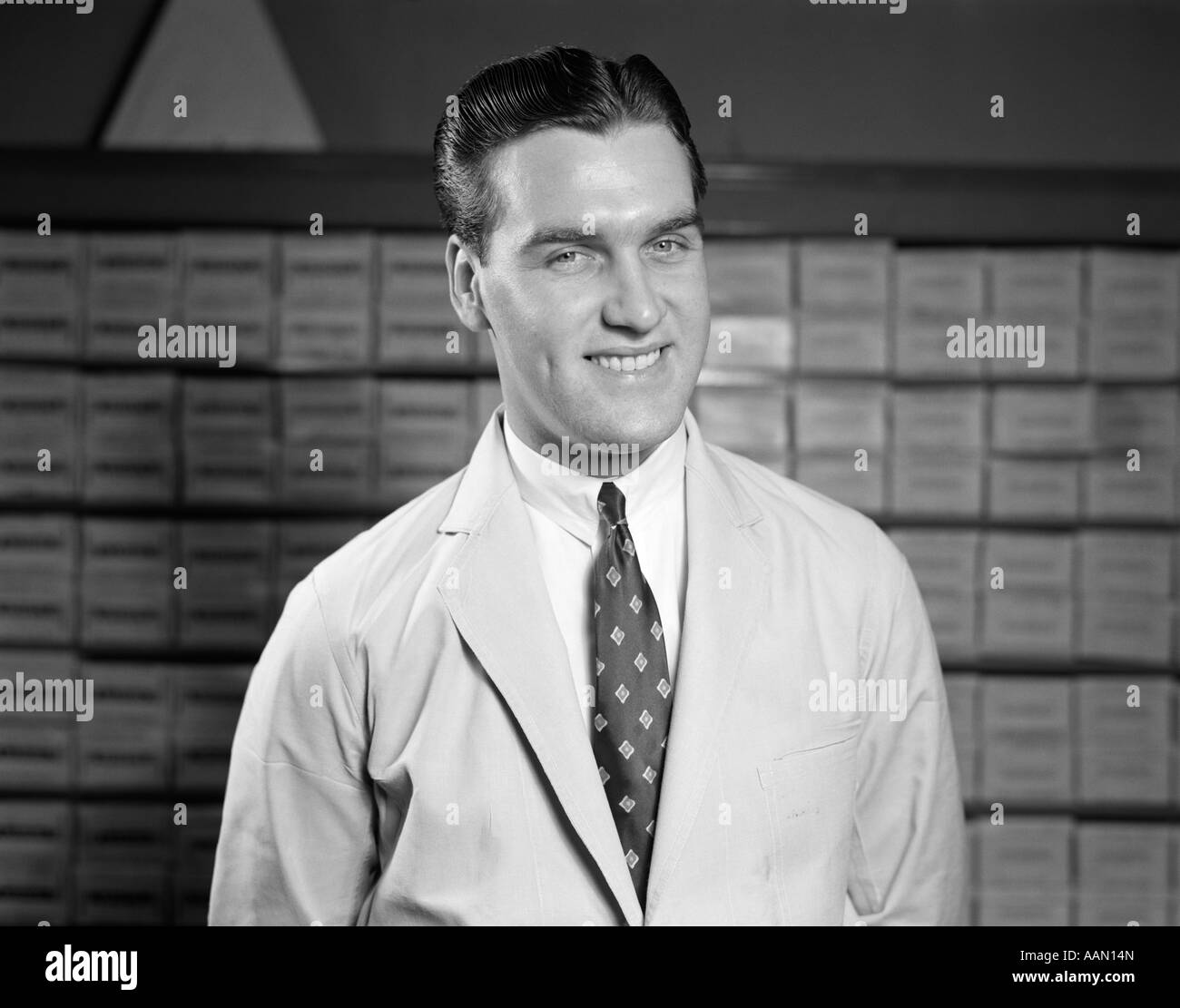 Negli anni quaranta anni cinquanta venditore in camice bianco e cravatta ritratto sorridente al farmacista di inventario IN BACKGROUND Foto Stock