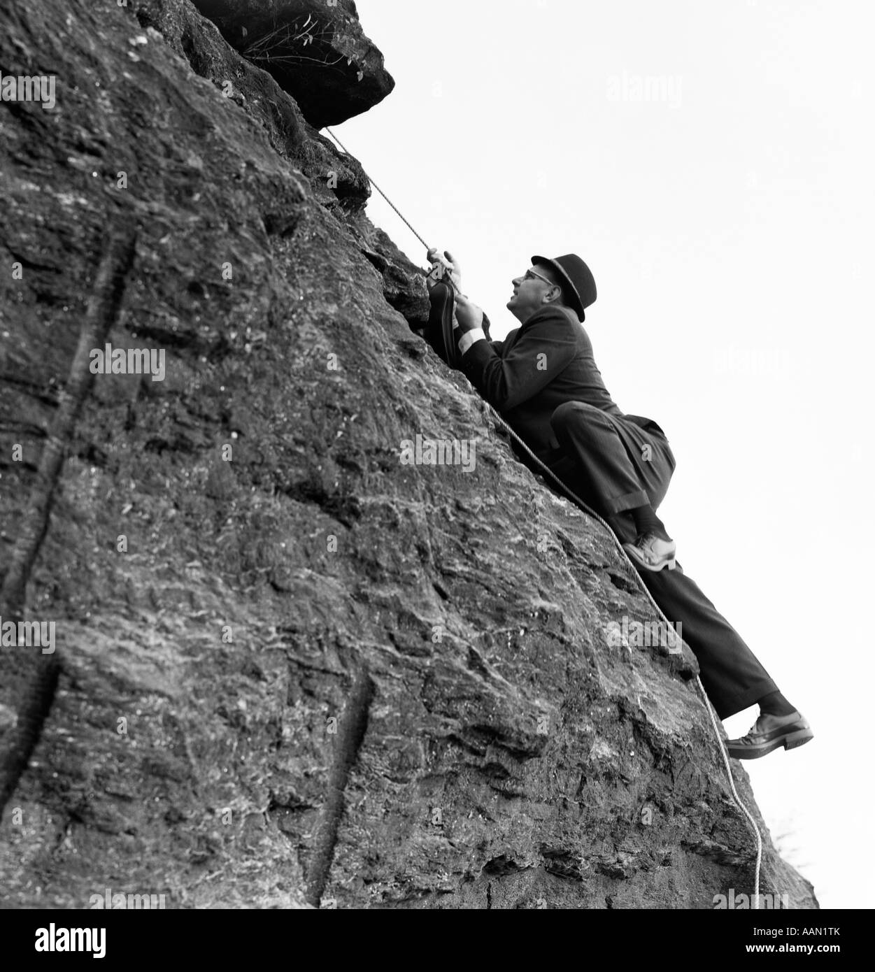 Anni sessanta imprenditore nel cappello e tuta rock climbing tenendo la corda Foto Stock