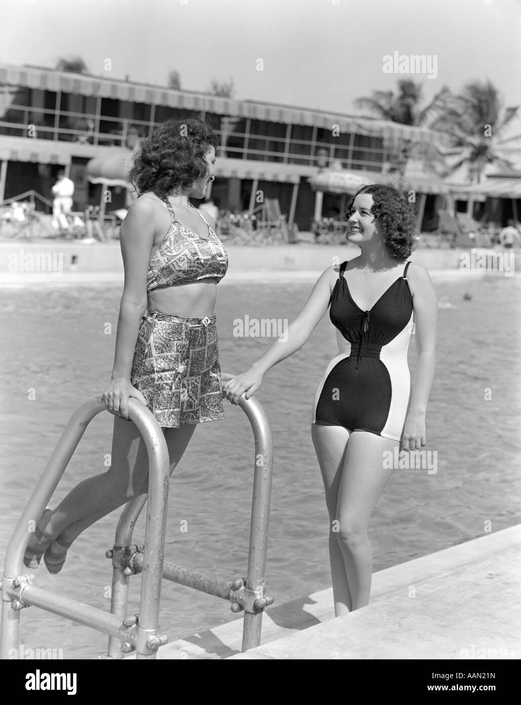 Trenta anni quaranta due donne in costumi da bagno in piedi a fianco della piscina una appoggiata sulla Scaletta per piscina Foto Stock