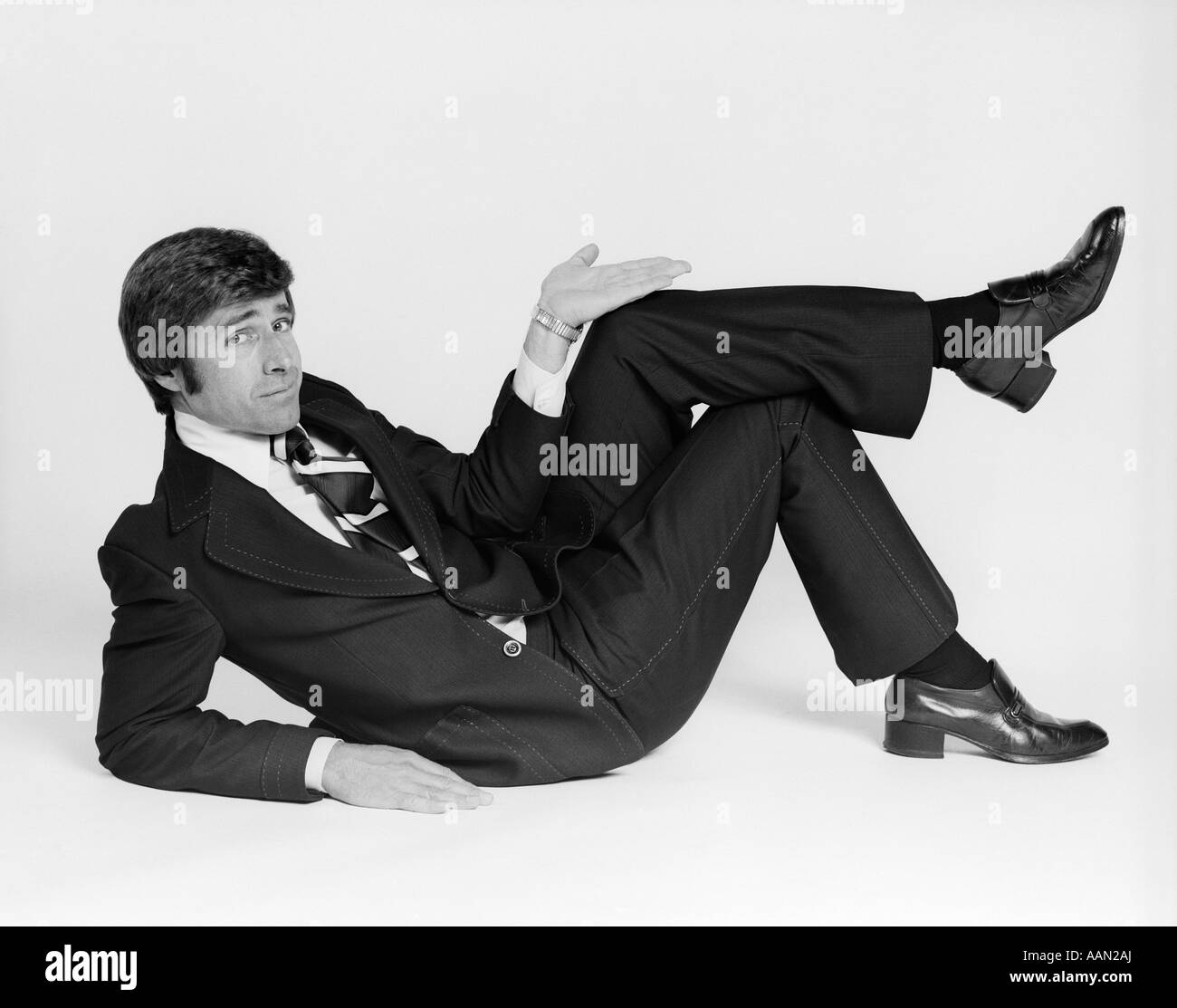 Anni Settanta BUSINESS uomo disteso sul lato rendendo gesto con la mano Foto Stock