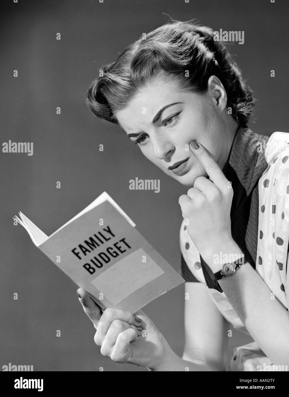 Anni Cinquanta la donna nel grembiule dito sulla guancia GUARDANDO AL BILANCIO FAMILIARE PRENOTA Foto Stock