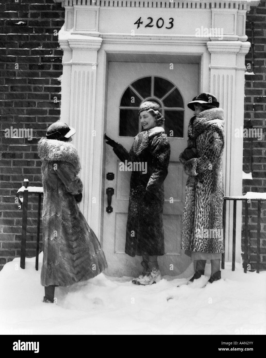 1930s 3 donne pellicce porta anello bell edificio in mattoni NEVE Foto Stock