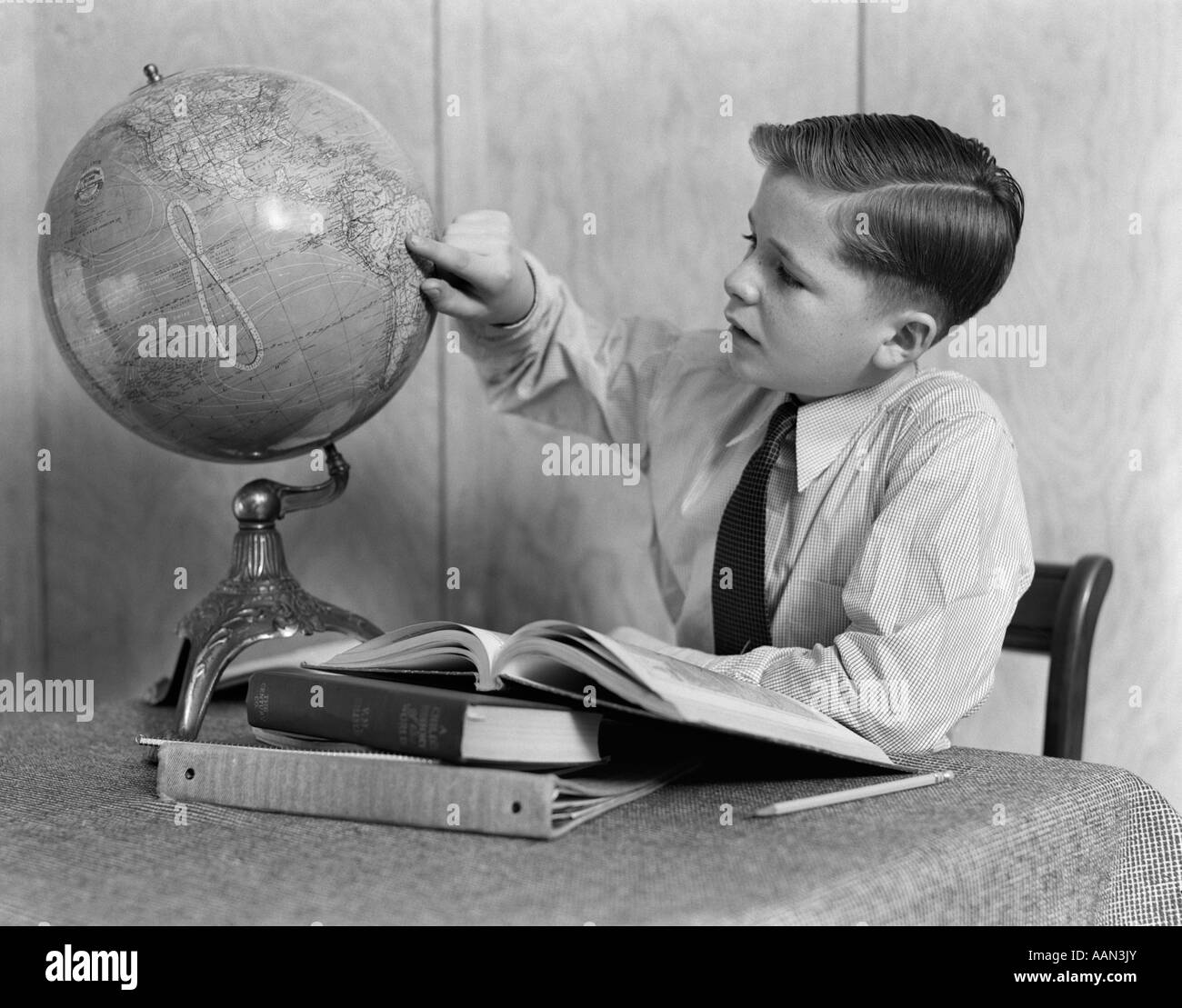 1930s 1940s giovane ragazzo a studiare con libri e Globo mondo puntando a AMERICA DEL SUD Foto Stock