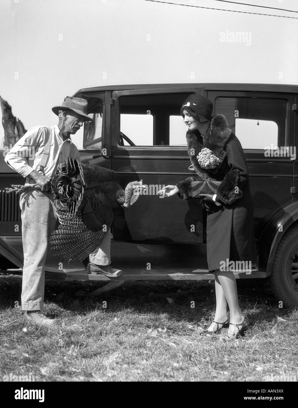 1920s l'agricoltore che detiene la Turchia a parlare con una donna vestiti alla moda tenuto in mano alla Turchia NELLA PARTE ANTERIORE DELLA MACCHINA Foto Stock
