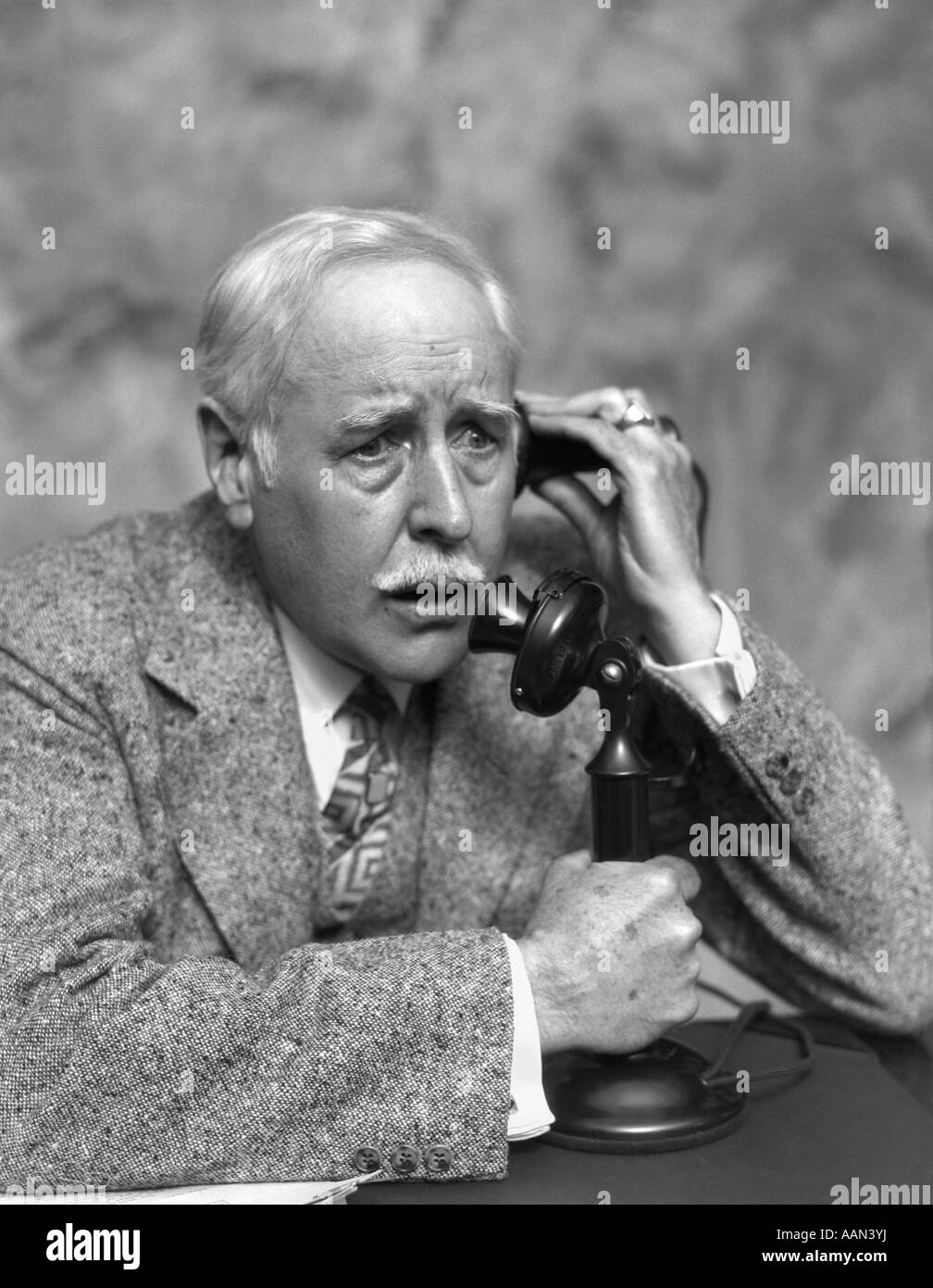 1920s 1930 anziani interessati preoccupato uomo parlando sul candelabro telefono BUSINESS MAN TWEED SUIT espressione seria Foto Stock