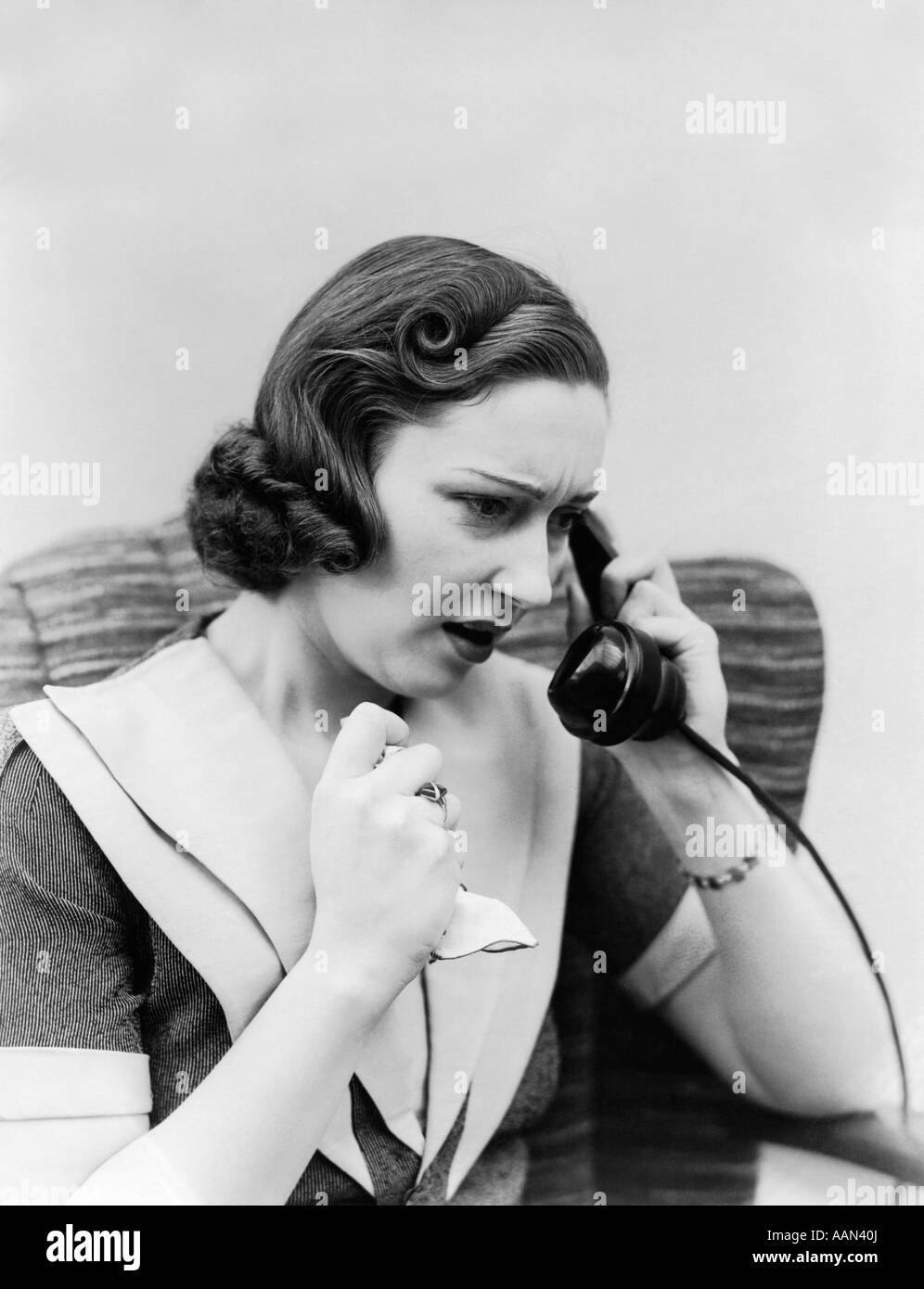 1930s donna parlando al telefono tenendo fazzoletto con espressione preoccupata Foto Stock