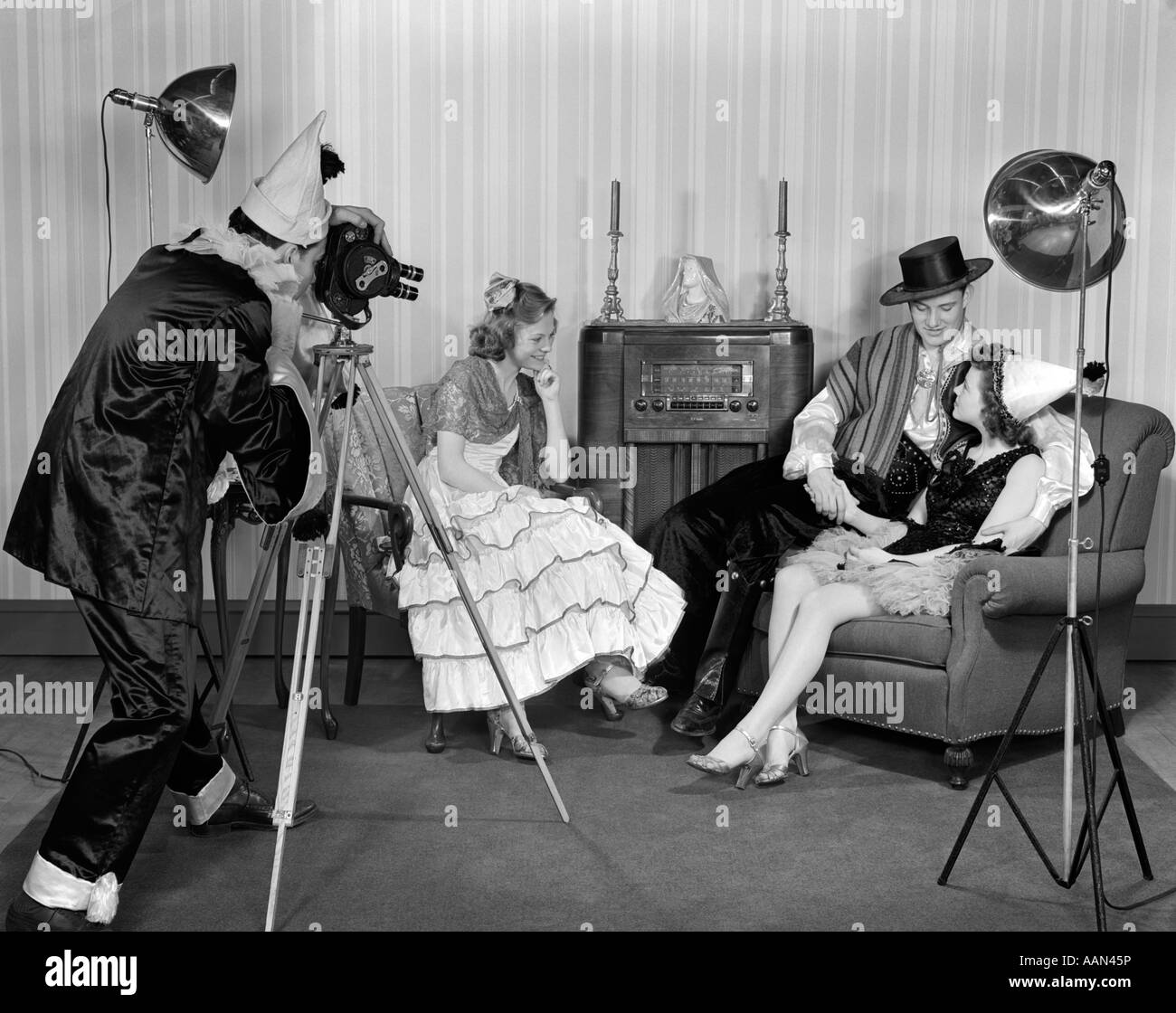 1940s costume gruppo di adolescenti uomini & donne riprese con una macchina fotografica del film in un salotto con poltrone e modello a pavimento AUTORADIO Foto Stock