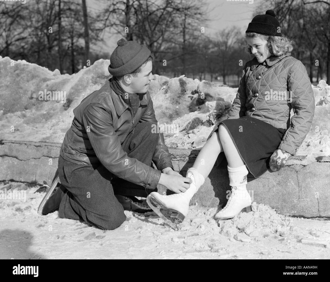 1930s 1940s TEENAGE MATURA IN KNIT CAPS & giacche invernali inginocchiato BOY legatura di pattini da ghiaccio per la ragazza Foto Stock