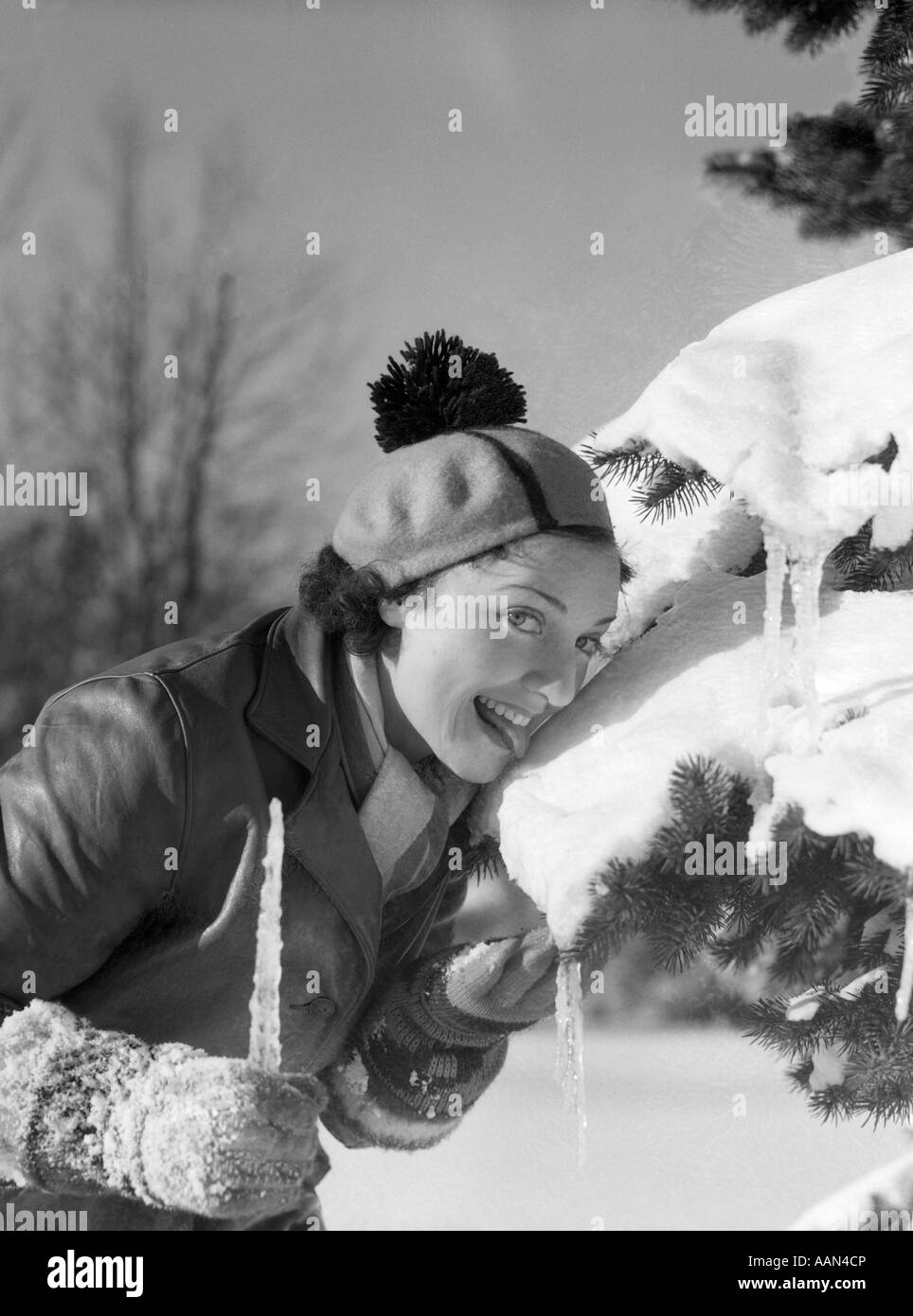 1930s 1940s sorridente donna stupida leccare la neve FUORI DI PINO ramo  indossando il cappello con pom pom infiorescenza staminifera guardando la  fotocamera Foto stock - Alamy