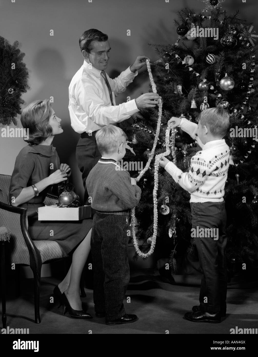 Anni sessanta PADRE DI FAMIGLIA MADRE DI DUE FIGLI DI FRESATURA AD ALBERO DI NATALE CON la stringa di pop-corn Foto Stock