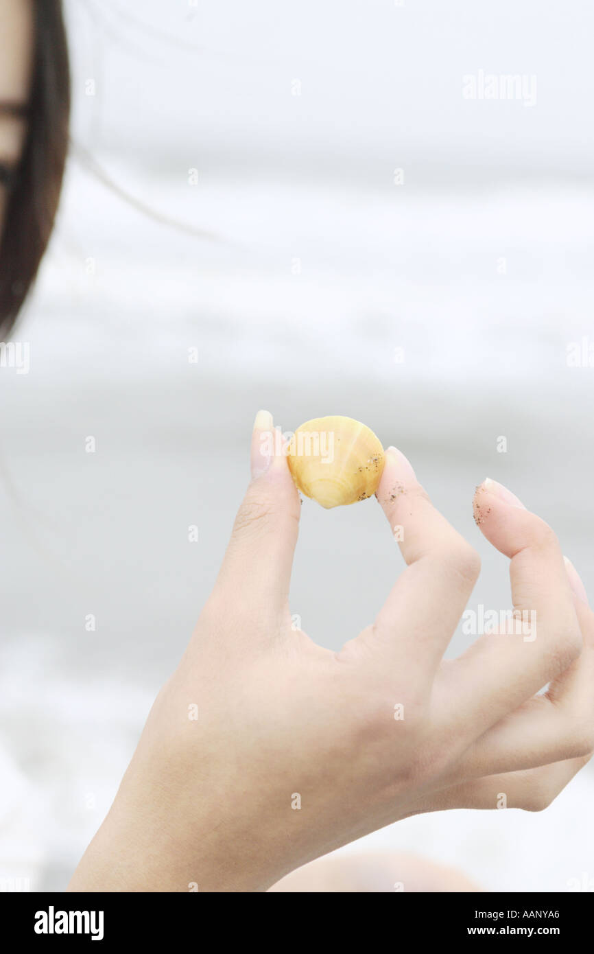 Una giovane donna in possesso di una shell Foto Stock