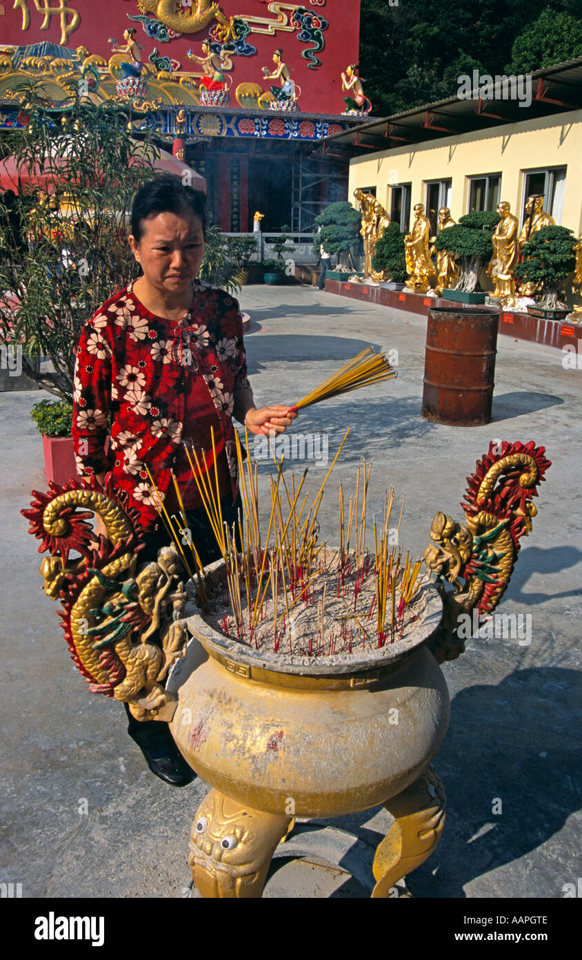 Donna immissione bruciare bastoncini di incenso in pentola, Diecimila Buddha Monastero, Sha Tin, Nuovi Territori di Hong Kong, Cina Foto Stock