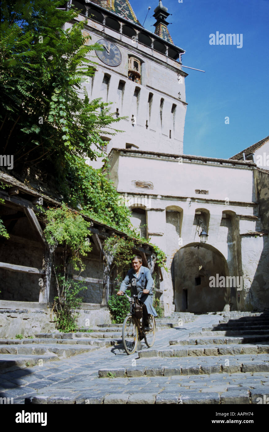 Uomo in bicicletta attraverso l'ingresso alla città vecchia medievale di Sighisoara Romania Foto Stock