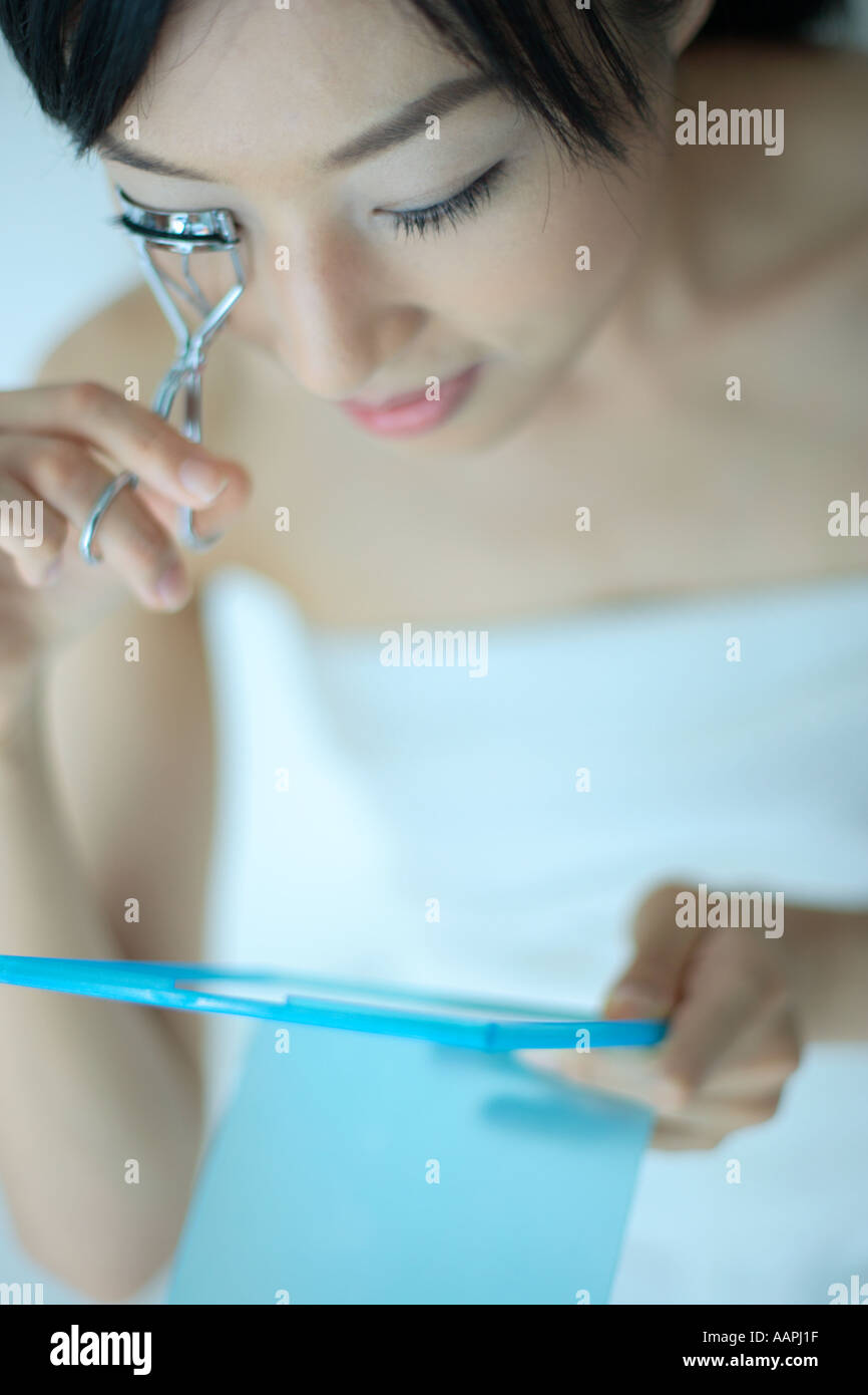 Una giovane donna utilizzando arricciatore ciglia Foto Stock