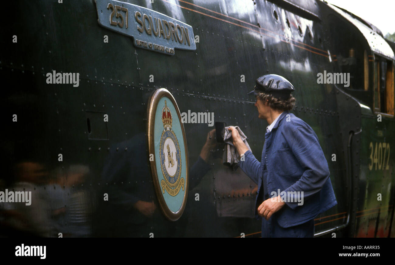 Uomo in tuta sul lato della grande battaglia della Gran Bretagna classe locomotiva a vapore in corrispondenza di una stazione di conservazione del sito del club Foto Stock