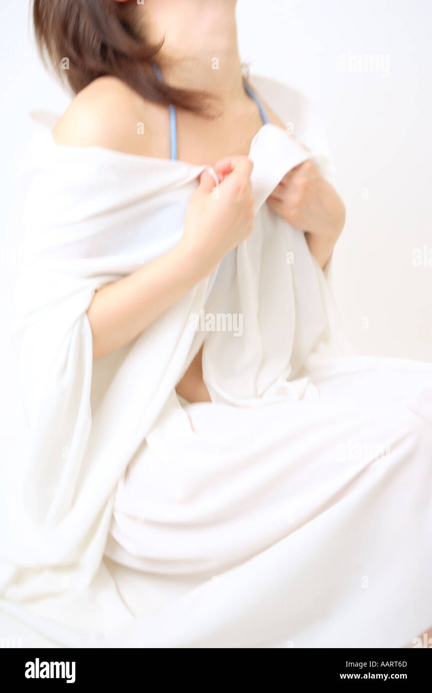 Una giovane donna che copre con foglio bianco Foto Stock