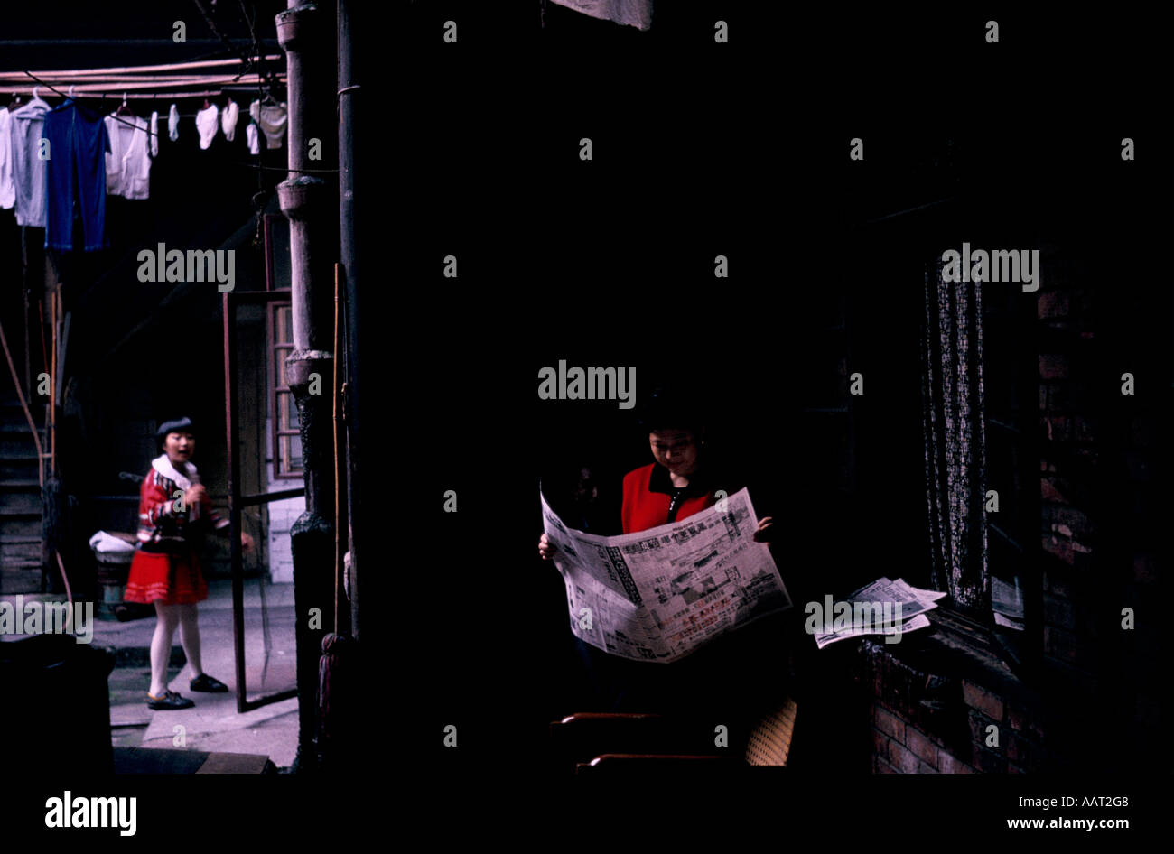 Provincia di Sichuan in Cina 1998 all'interno di una casa di una donna legge le carte al di fuori di un bambino sta sotto una comune linea di lavaggio Foto Stock