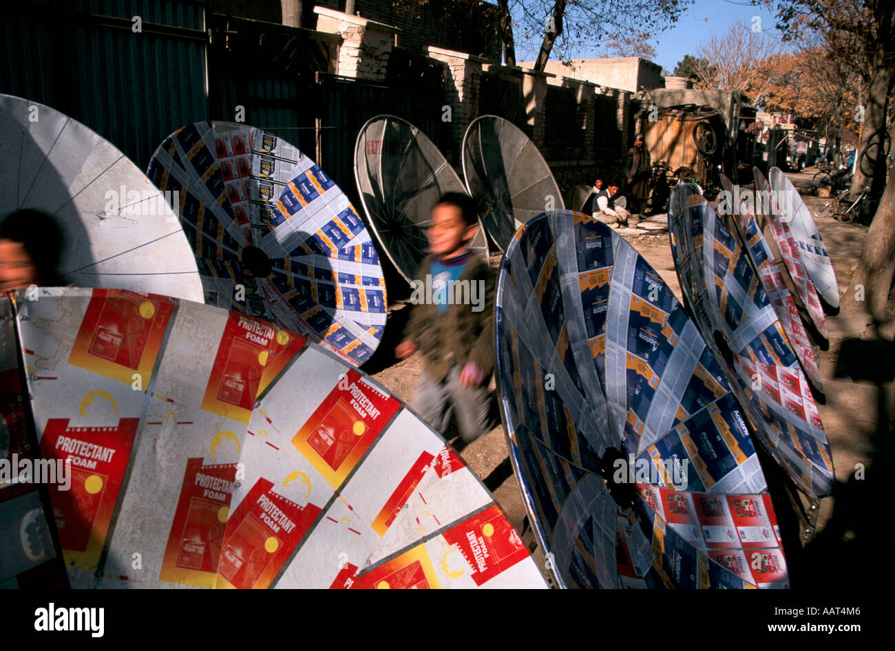 Bambini riciclare la latta in parabole satellitari a piedi nel centro della città di Kabul a vendere loro Foto Stock