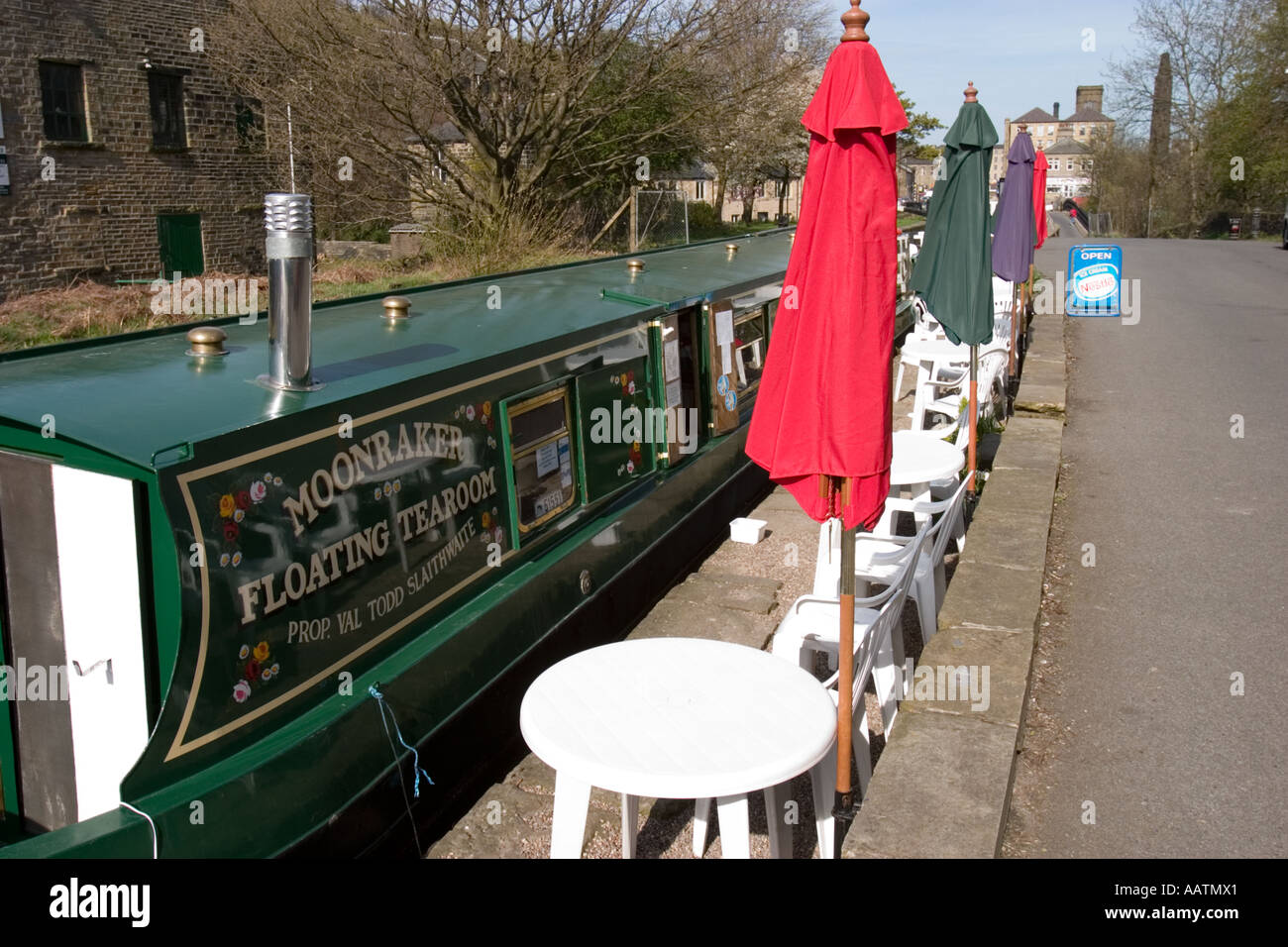 Narrowboat utilizzato come cafe a Huddersfield stretto canale Slaithwaite con tavoli e ombrelloni sul canal bank Foto Stock
