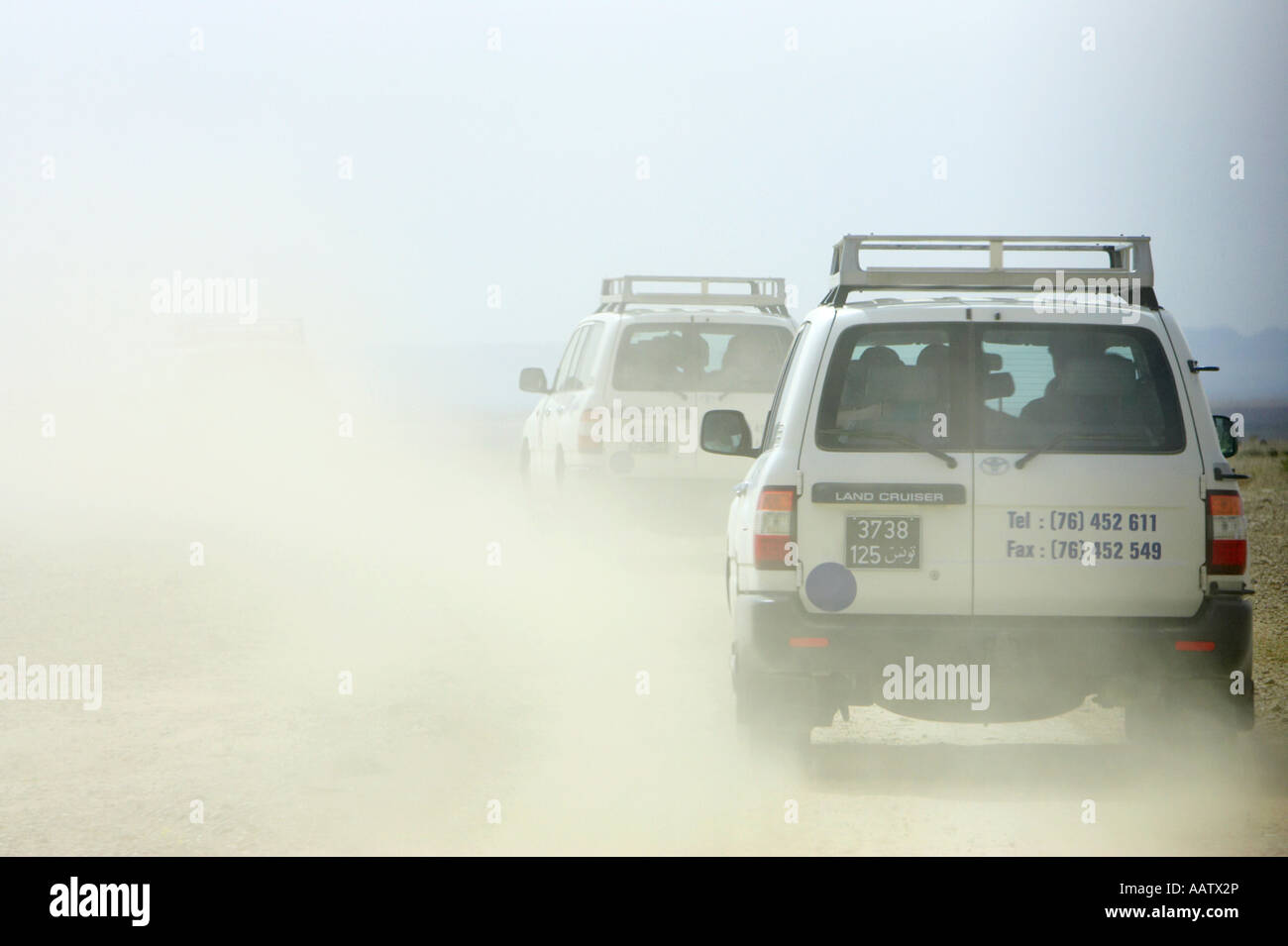 Off road tourist veicoli 4x4 alzare nuvole di polvere guidando attraverso il deserto in Tunisia in un convoglio di Toyota landcruisers Foto Stock