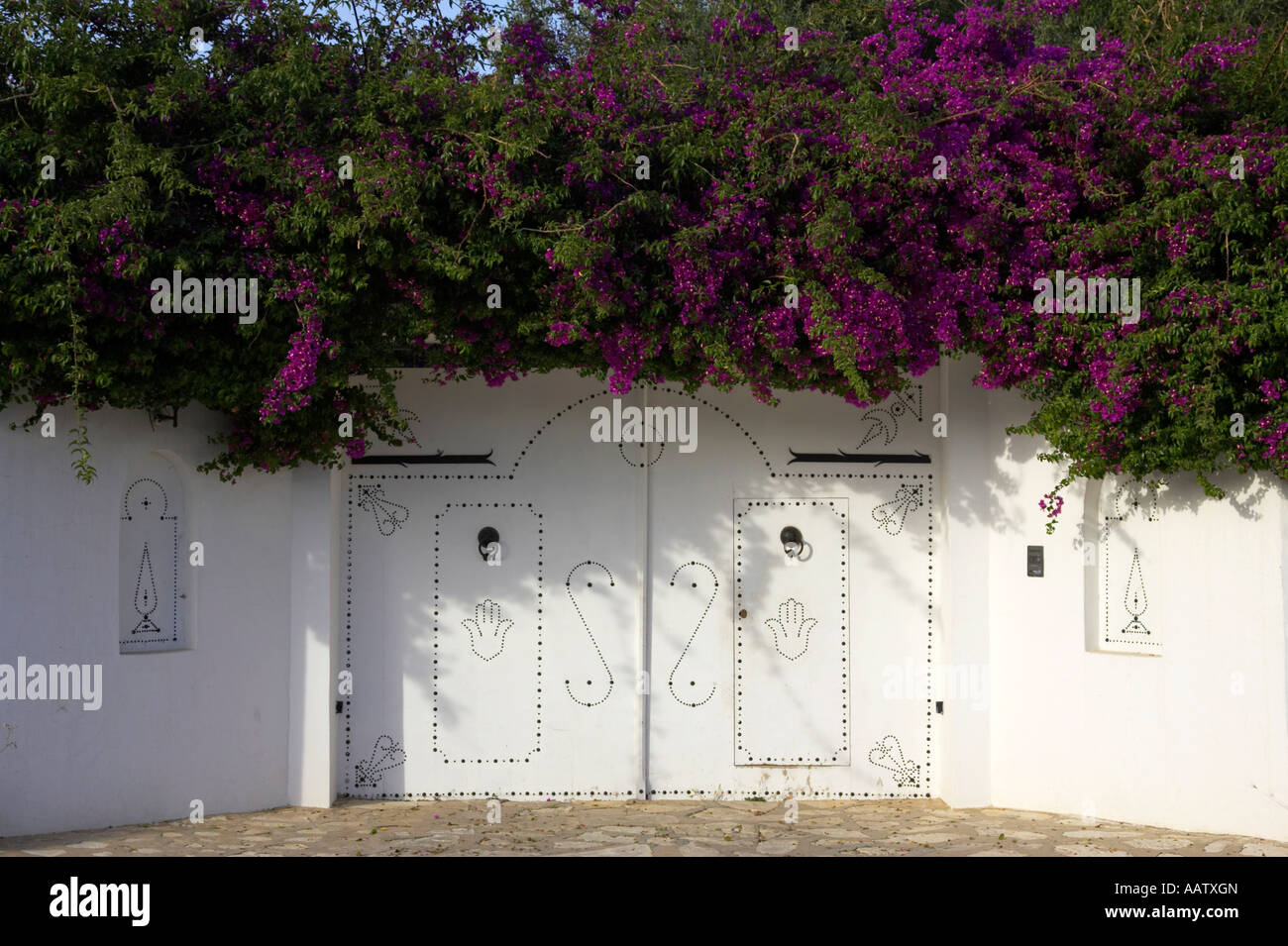 Decorato in bianco porte modellato con cespugli di fiori viola che copre i cancelli hammamet tunisia Foto Stock