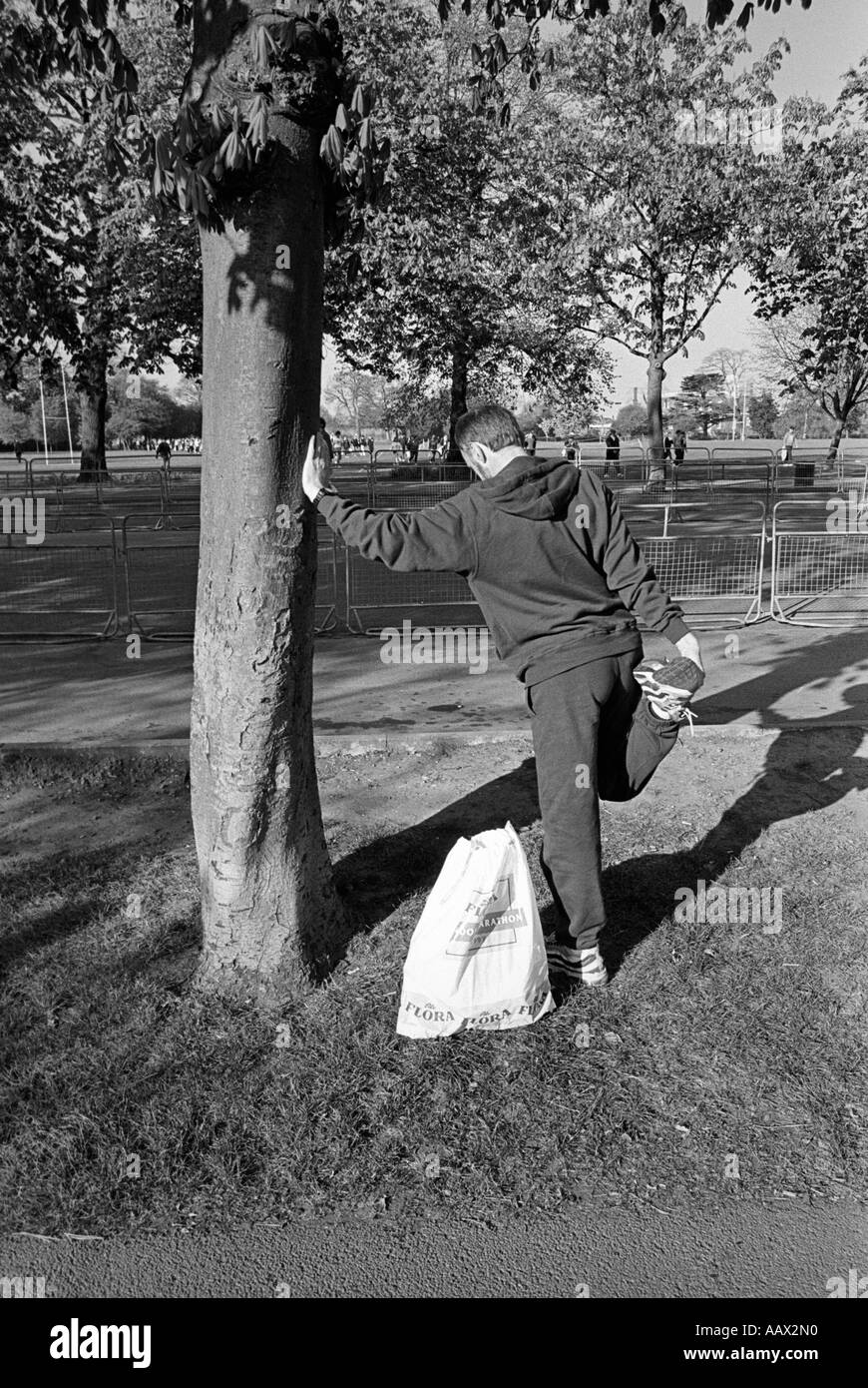 Un runner stretching nel parco di Greenwich prima della Maratona di Londra Foto Stock