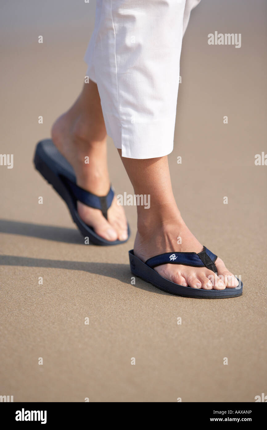 Femmina 20 s 30s piedi camminando sulla spiaggia sabbiosa di indossare flip flop Foto Stock