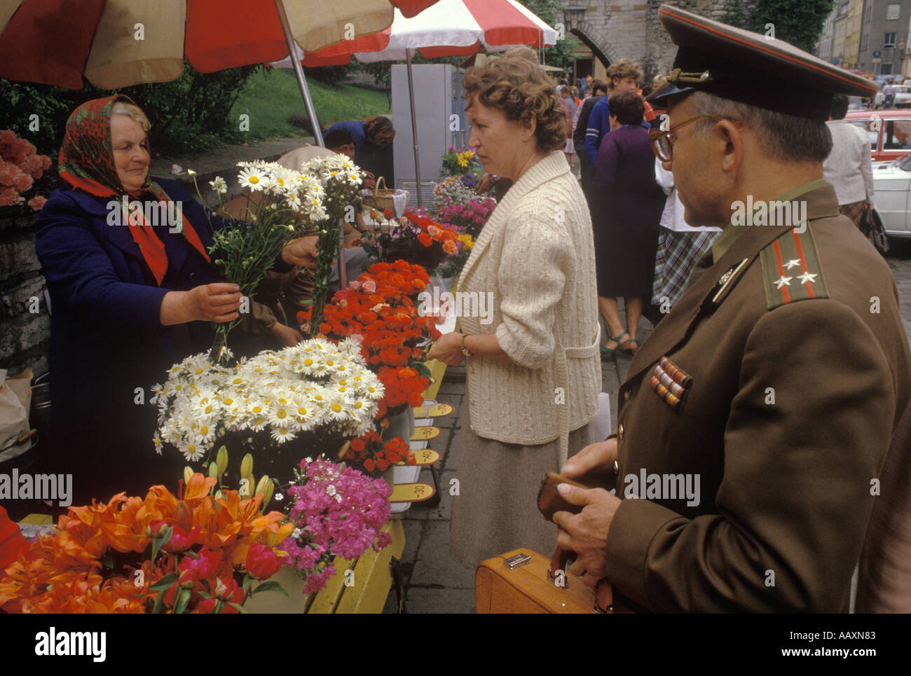 Unione Sovietica, Tallinn Estonia anni 1980 Un soldato russo aspetta di comprare dei fiori da una donna estone al mercato dei fiori di strada di Viru. Un "libero mercato". Foto Stock