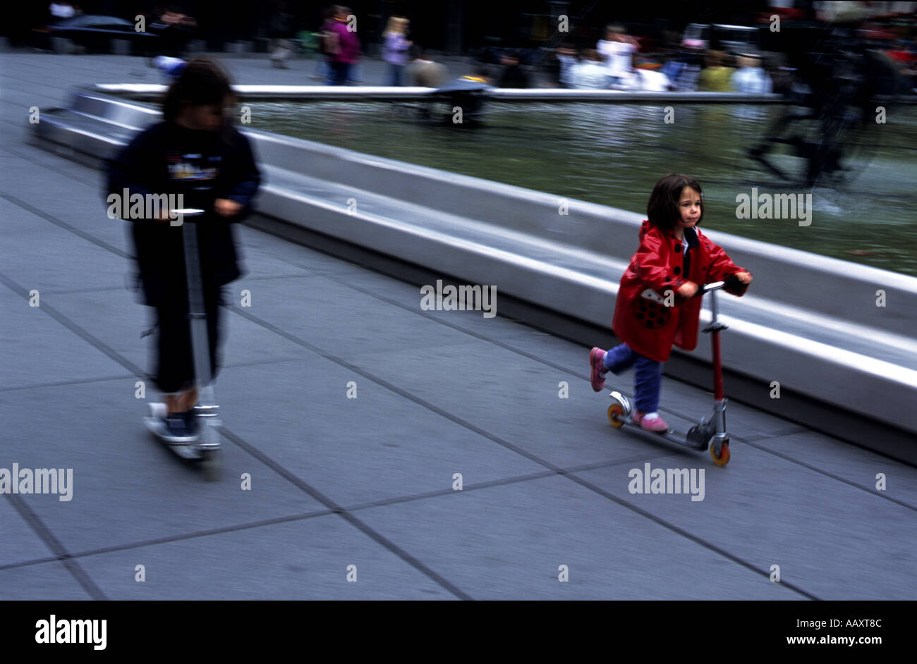 Bambini su scooter gara attorno alle fontane vicino al centro Pompidou a Parigi Francia Foto Stock