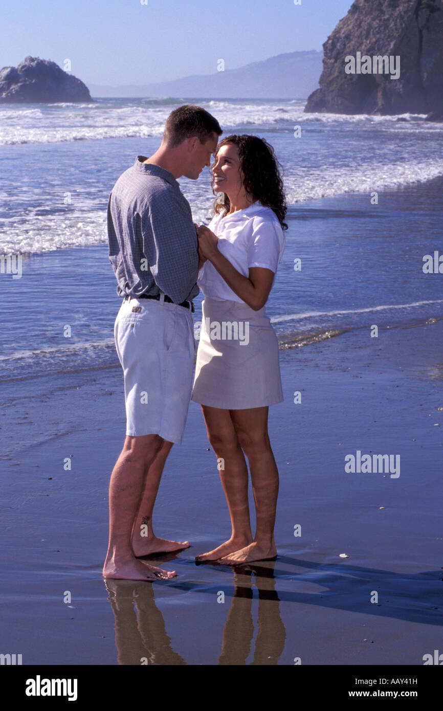 Amare giovane in amore tenendo le mani sulla spiaggia cercando in ogni altri occhi lungo la costa della California Foto Stock