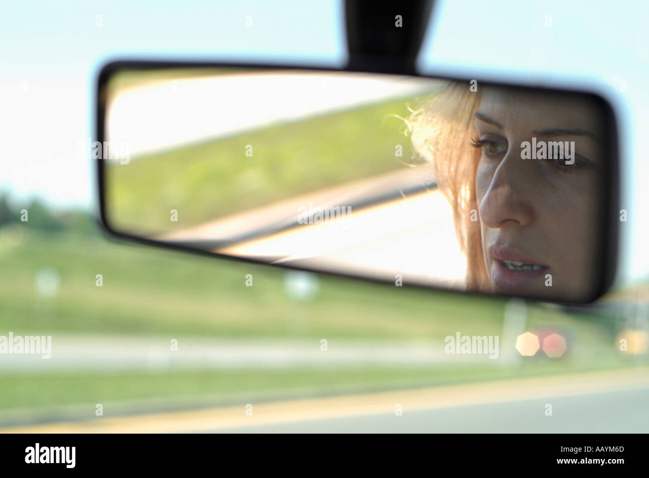 Donna in specchietto retrovisore di una vettura guida in autostrada Foto Stock