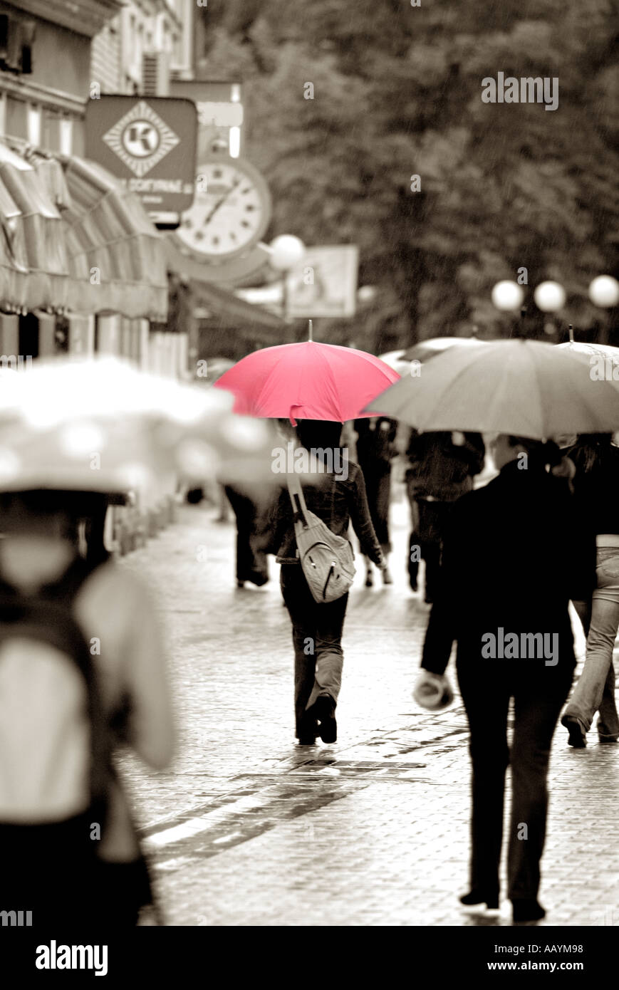 Giovane donna con un ombrello rosso in una strada trafficata in un giorno di pioggia Foto Stock
