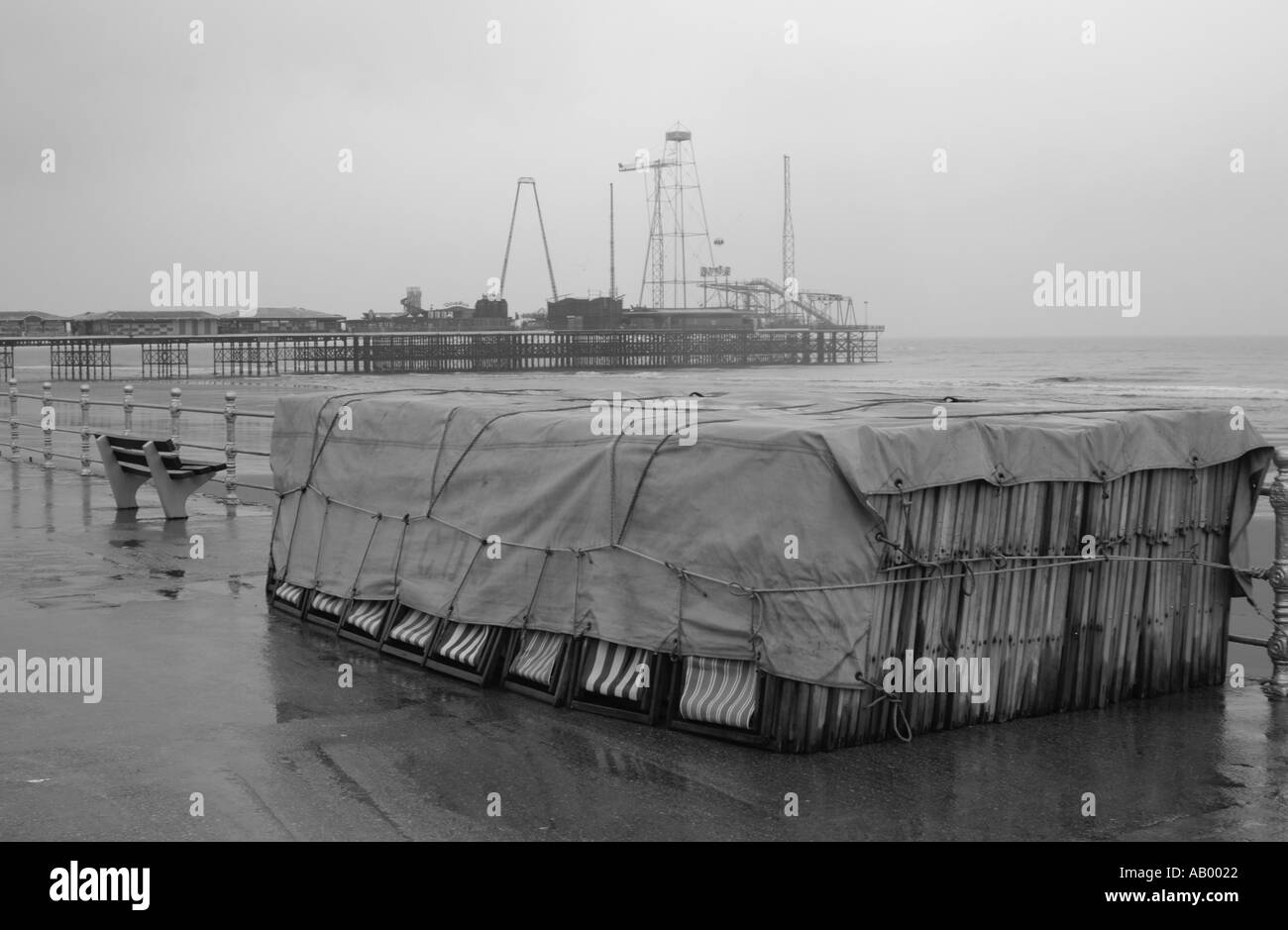 Sedie a sdraio legato sotto un telone sul lungomare di Blackpool sotto la pioggia Foto Stock