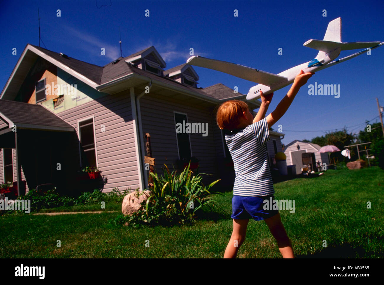 Giovane ragazzo giocando con il modello di aereo nel cortile di casa Foto Stock