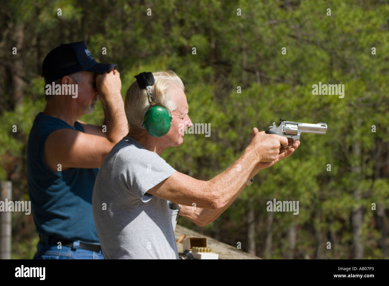Son guarda come un cittadino anziano maschio punta la pistola durante la pratica di tiro al poligono di tiro nella Ocala National Forest Ocala Florida USA Foto Stock