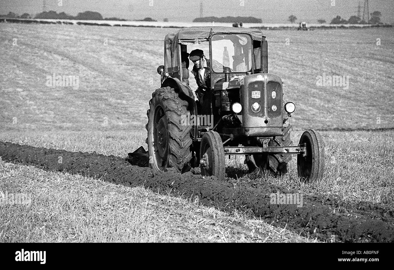 L'uomo sul vecchio modello trattore a concorso di aratura di tentare di aratro completamente dritto solchi. Foto Stock