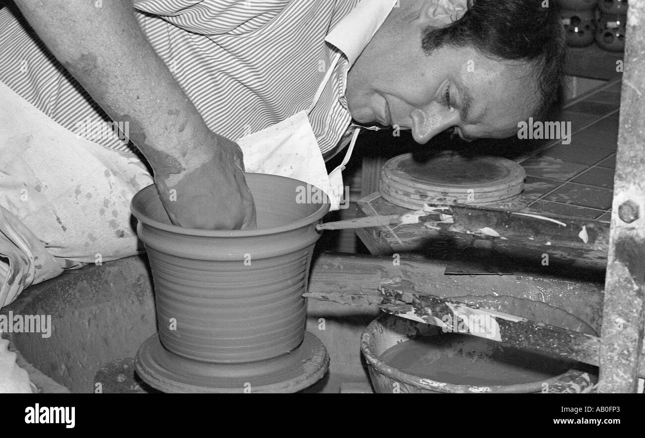 Chiudere il colpo di potter usando le mani dentro la filatura argilla umida a forma di vaso. Foto Stock