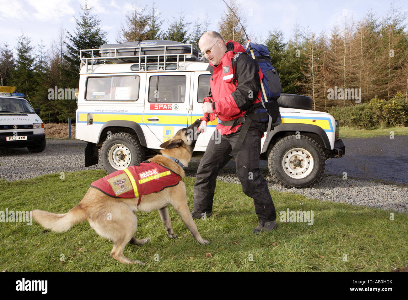 Galloway Mountain Rescue training di un giovane cane con Landrover veicolo di soccorso dietro la Scozia UK Foto Stock