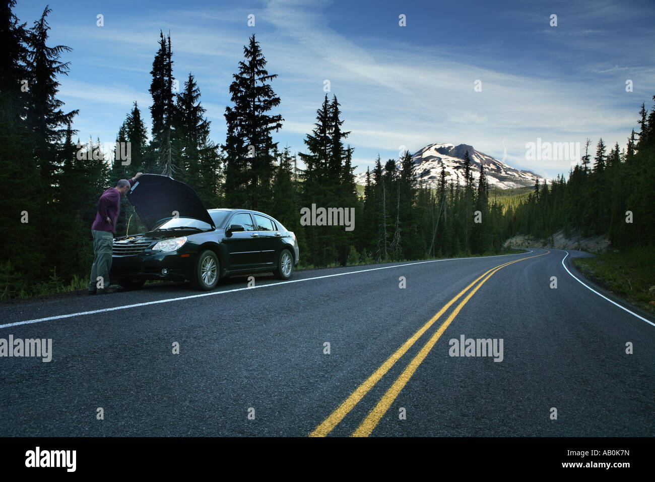Uomo in piedi sul lato della strada con sfondato auto Foto Stock