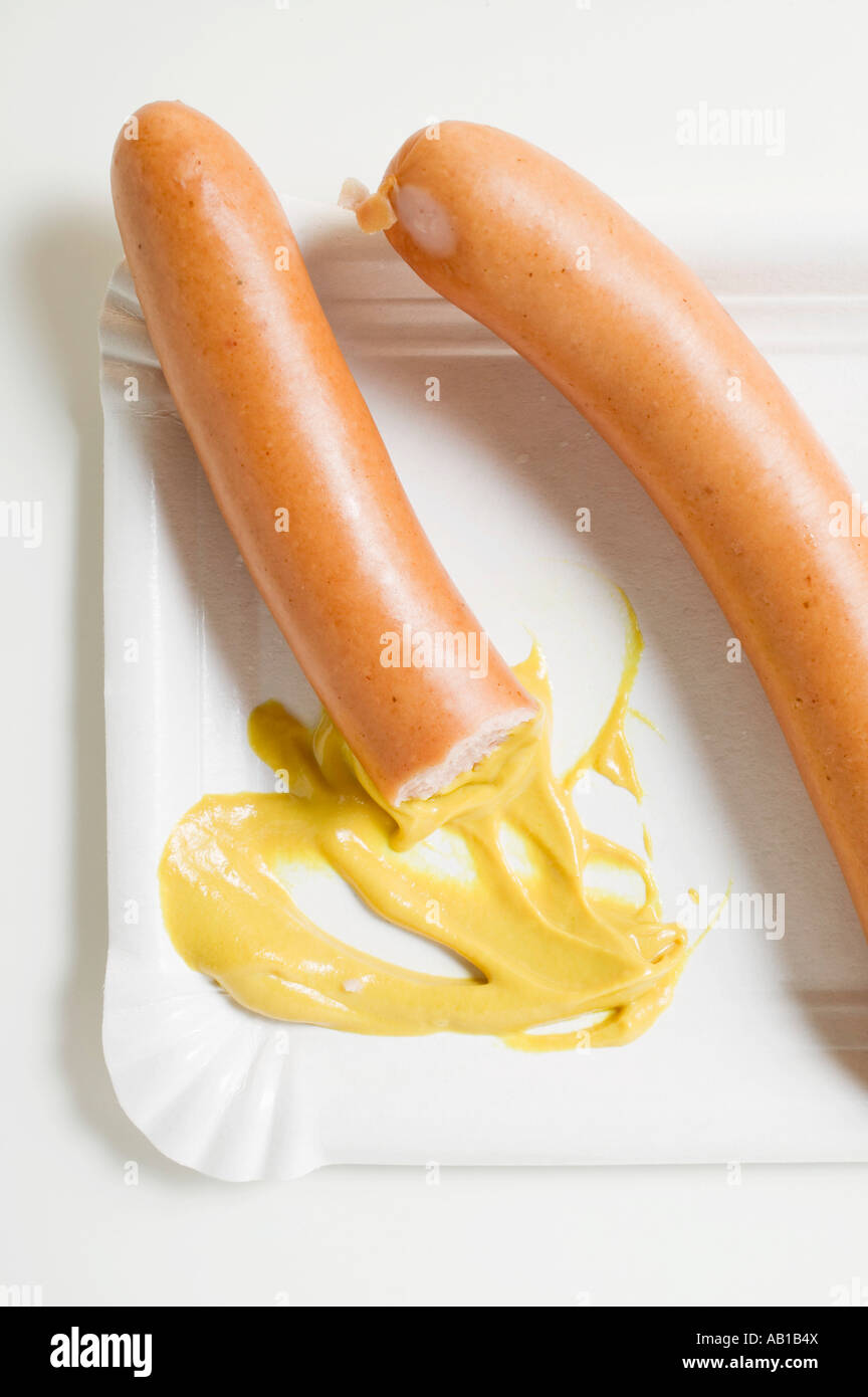 Wurstel in parte mangiato con senape sul piatto di carta FoodCollection Foto Stock