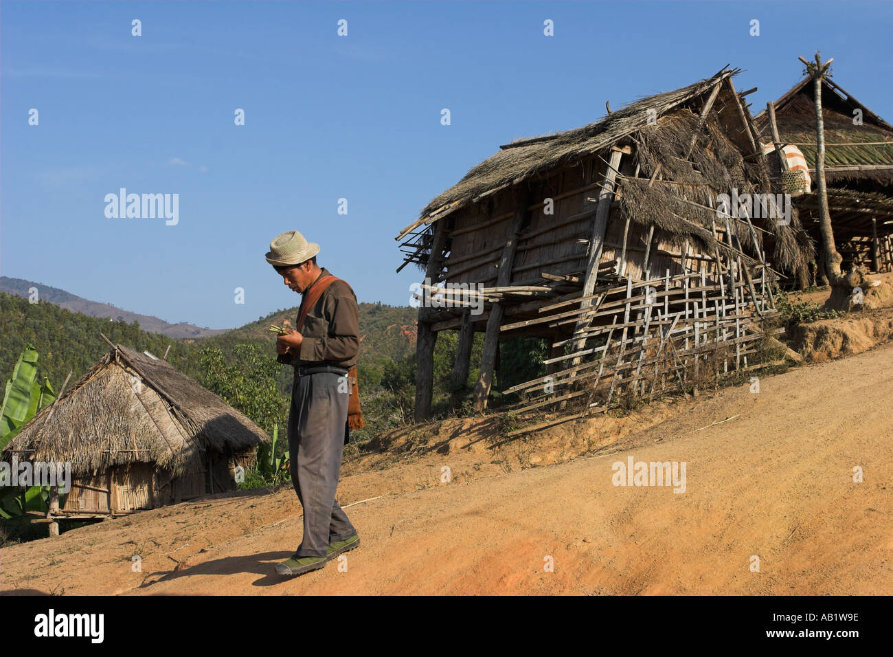 Myanmar stato Shan Kengtung Ann Village man walking passato case in paglia Foto Stock
