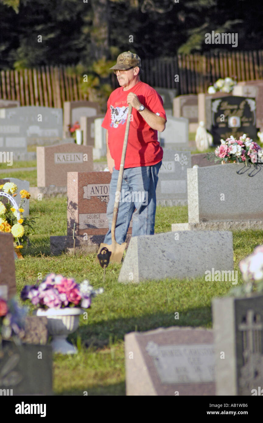 I marcatori di tomba nel cimitero in Sud America USA e la pulizia del sito con le statue di Maria e Gesù e fiori Foto Stock