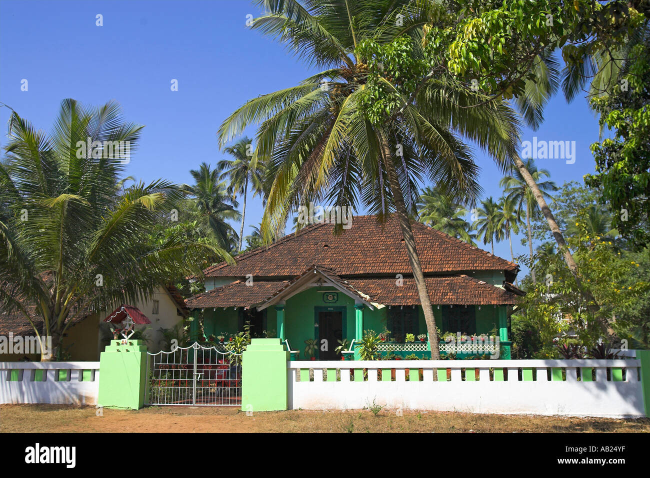 Attraente verde su un unico piano casa piastrellato con palme e vasi di piante tropicali Goa in India Foto Stock