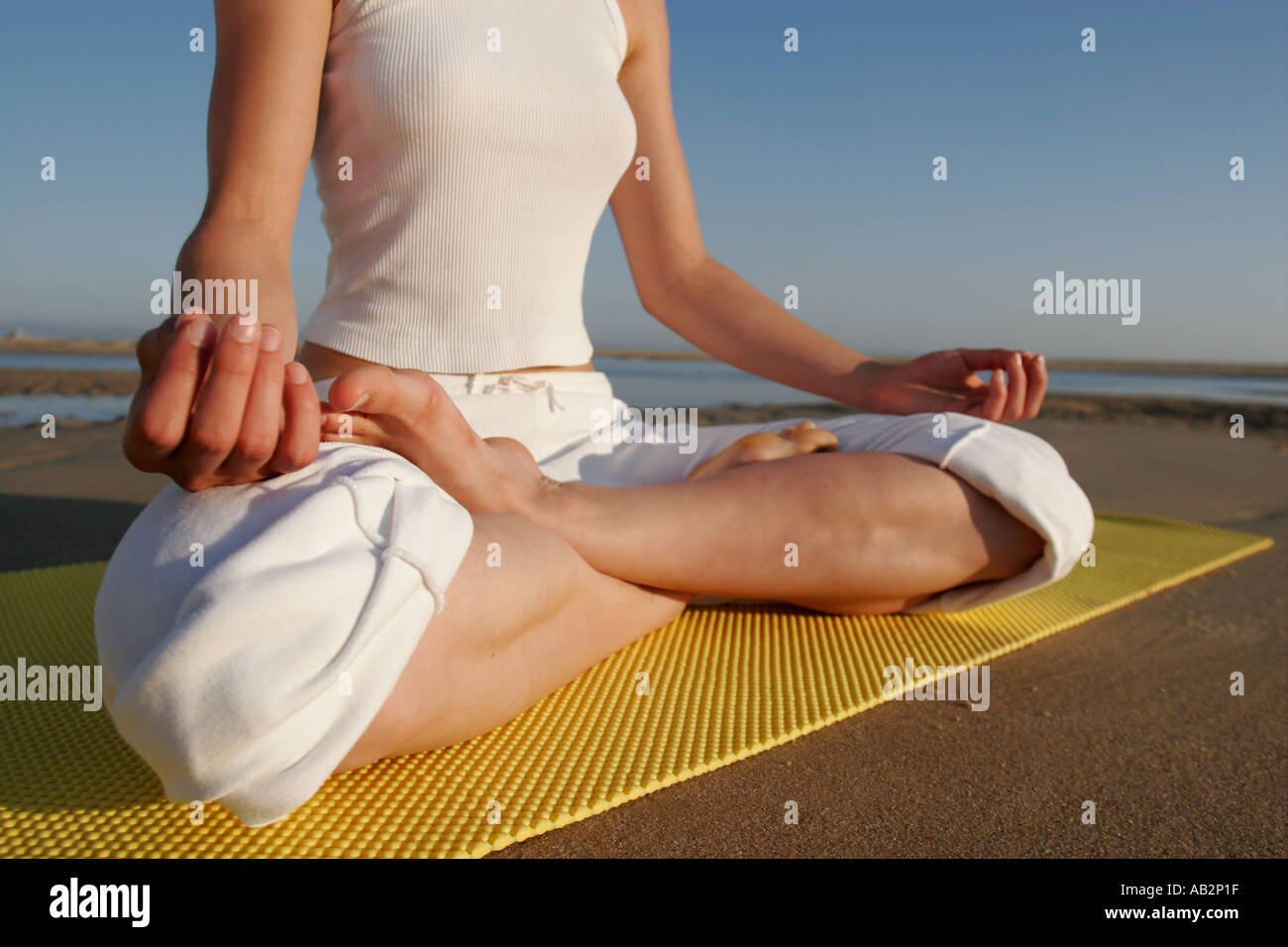 Gambe incrociate della donna nella meditazione seduta su giallo materassino yoga Foto Stock